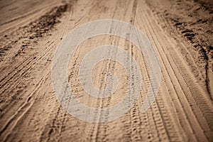 Selective blur on a tire track on a sand, traces of tyres and wheels of cars and vehicles driving off road on a dirt path, a sandy