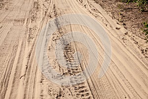 Selective blur on a tire track on a sand, traces of tyres and wheels of cars and vehicles driving off road on a dirt path, a sandy