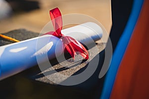 Selective and close-up focus of a university graduate holds a degree certificate and graduation cap celebrates in the graduation c