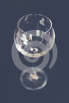 Selective closeup focus shot of a clear long-stemmed wine glass with a black background