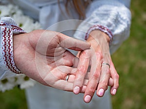 Selective closeup shot of a Caucasian couple wearing rings holding hands