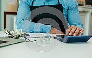 Selective focus on accounting man hand using calculator, calculating income, budget, profit with dollar bank notes after selling