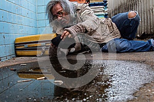 Selective focus Addiction aged man sitting on dirty street with old blanket excited with money donation, unemployed homeless get