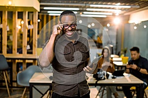 Selective focus of african american man in casual wear holding digital tablet and colleagues at workplace in modern