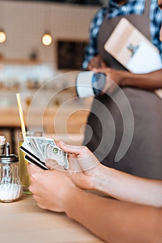 selective focus of african american waiter taking cash payment