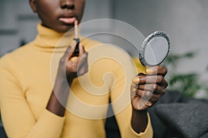 Selective focus of african american woman holding mirror and photo
