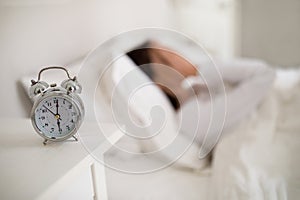 Selective focus on alarm on bedside table over sleeping lady