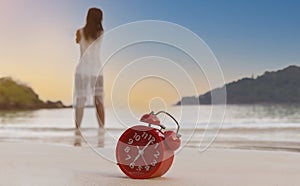 Selective focus of Alarm clock on the bech with woman playing yoga and stretching muscles on the beach sunlight in morning. Health