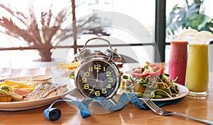 Selective focus of Alarm clock and Diet plan with Intermittent fasting as the Time to lose weight , eating control-Diet concept