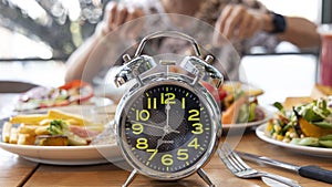 Selective focus of  Alarm clock with  young man eating a healthy food as Intermittent fasting, time-restricted eating-Diet