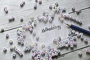 Selective focus of alphabet beads,pencil and paper written with Methodology on white wooden background