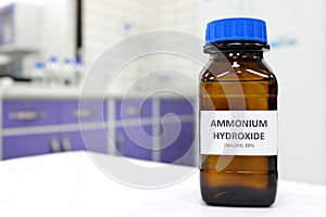 Selective focus of ammonium hydroxide or ammonia solution in glass amber bottle inside a chemistry laboratory with copy space.