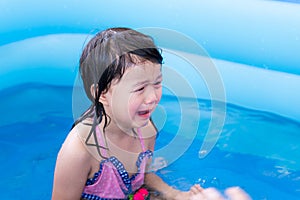 Selective focus  Asian girl crying in blue rubber pool. She cried from being teased by her friend while playing in the water.