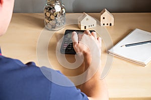 Selective focus at Asian men hand using calculator to calculate saving plan or home mortgage loan to buy house. Home ownership