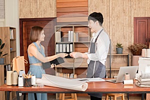 Selective focus of asian woman buying dress in tailor-made clothing store and pay by credit card. Young sales man gives shopping