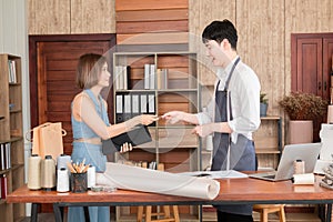 Selective focus of asian woman buying dress in tailor-made clothing store and pay by credit card. Young sales man gives shopping