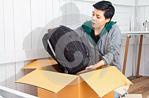 Selective focus,Asian young man Unpack the postal box,parcel while He was surprised and happy sitting on Wooden floor at home