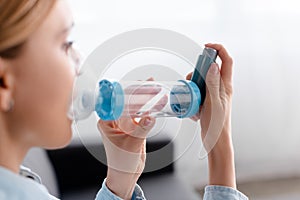 Focus of asthmatic woman using inhaler photo