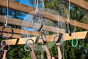 selective focus, athletes hands at a hanging obstacle with metal rings at an obstacle course race, OCR