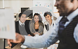 Selective focus on Attendee. African american men explaining the attendees snilling on a board, having graph papers at the