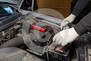 Selective focus an auto mechanic uses a multimeter voltmeter to check the voltage level in a car battery