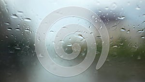 Selective focus background of rain on slanted windshield of a driving car on a rainy day