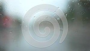Selective focus background of rain on slanted windshield of a driving car on a rainy day