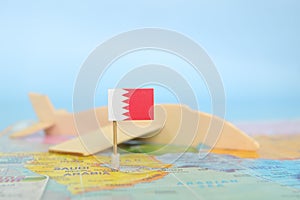 Selective focus of Bahrain flag in blurry world map and wooden airplane model. Bahrain as travel and tourism destination concept.