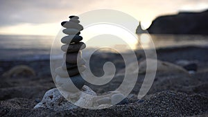 Selective focus. Balanced Pebble stone pyramid against blue sea on warm sunset. Zen stones on the sea beach, harmony