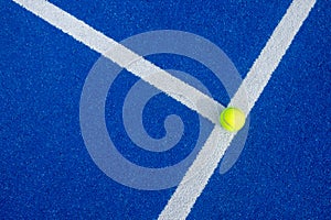 Selective focus of a ball on the white line of a blue paddle tennis court