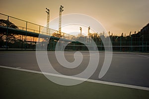 Selective focus on the baseline of tennis court with sunset sky background. Landscape of sport place.