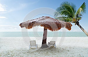 Selective focus beach chairs with umbrella wood and beautiful sand beach with coconut tree and andaman sea background tropical