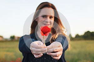 Selective focus of a beautiful woman holding a red poppies flower