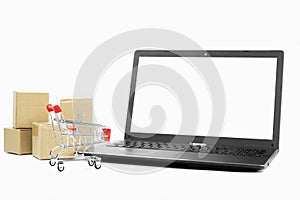 Selective focus, the blank screen laptop,red shopping cart and brown parcel box pile isolated on white background