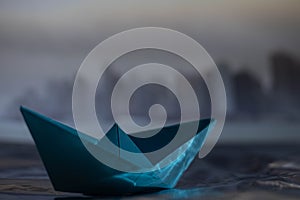 selective focus of a blue paper boat and New York Sky line on a rainy