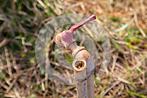 Selective focus with blurred background of grunge and rusty faucet installed in the field of remote rural area for people living