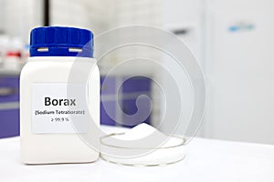 Selective focus of a bottle of borax chemical compound or sodium tetraborate beside a petri dish with solid powder substance