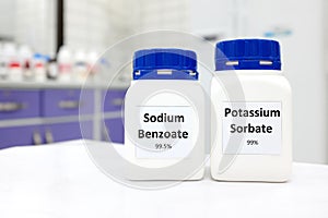 Selective focus of bottle of pure potassium sorbate and sodium benzoate food additive beside a petri dish with white solid powder