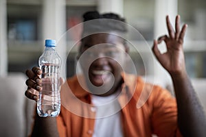 Selective focus on bottle of water in black guy hand