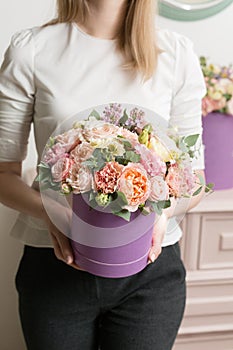 Selective focus on bouquet in lilac hatbox. beautiful luxury bunch of mixed flowers in womans hand. the work of the