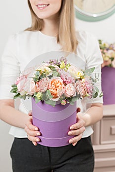 Selective focus on bouquet in lilac hatbox. beautiful luxury bunch of mixed flowers in womans hand. the work of the