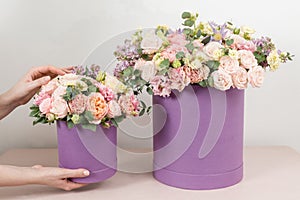 Selective focus on bouquet in lilac hatbox. beautiful luxury bunch of mixed flowers in womans hand. the work of the