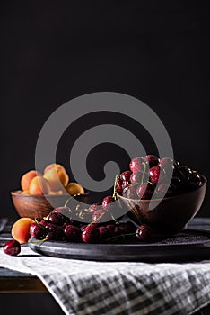 selective focus of bowls with ripe cherries and apricots on wooden table