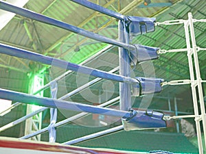 Selective focus of boxing ring / stage with its ropes, corner cushion, and lights on during night time