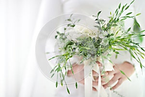 Selective focus the bride`s hand holding the wedding bouquet White and green tones. The elegant simplicity of the happy day