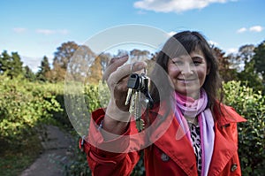 Selective focus. A brunette woman holds up a apartment house key in her hand