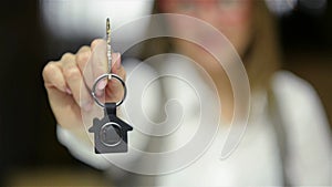 Selective focus of business lady holding new house key and smiling. Close up portrait of real estate agent.