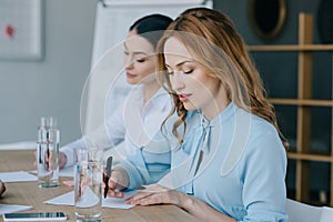 selective focus of businesswomen making notes at workplace