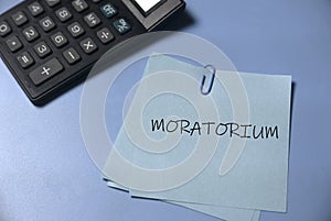 Selective focus of calculator and memo notes written with Moratorium on a blue background