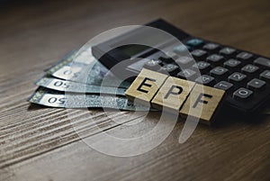 Selective focus of calculator, money and wooden cube written with alphabet EPF ( Employee Provident Fund